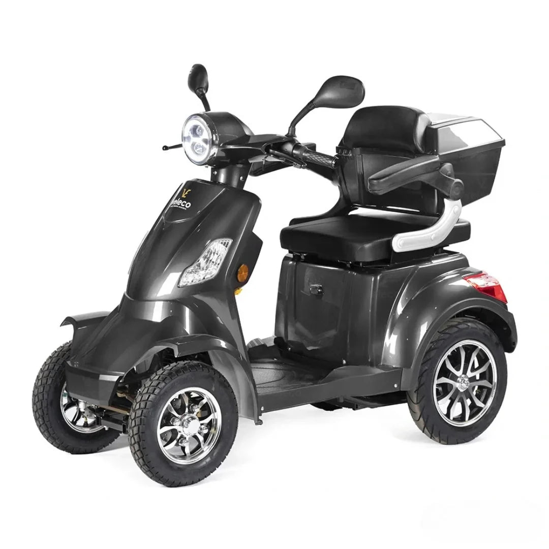 Izdelek je električni skuter, znamke Veleco, model Faster. Na sliki je prikazan skuter v temno sivi barvi, opremljen s tremi kolesi, kar zagotavlja stabilnost. Ima udobno sedežno površino, ročaje za nadzor in sprednje luči. Na zadnjem delu je tudi prostor za shranjevanje, kar povečuje funkcionalnost vozila.