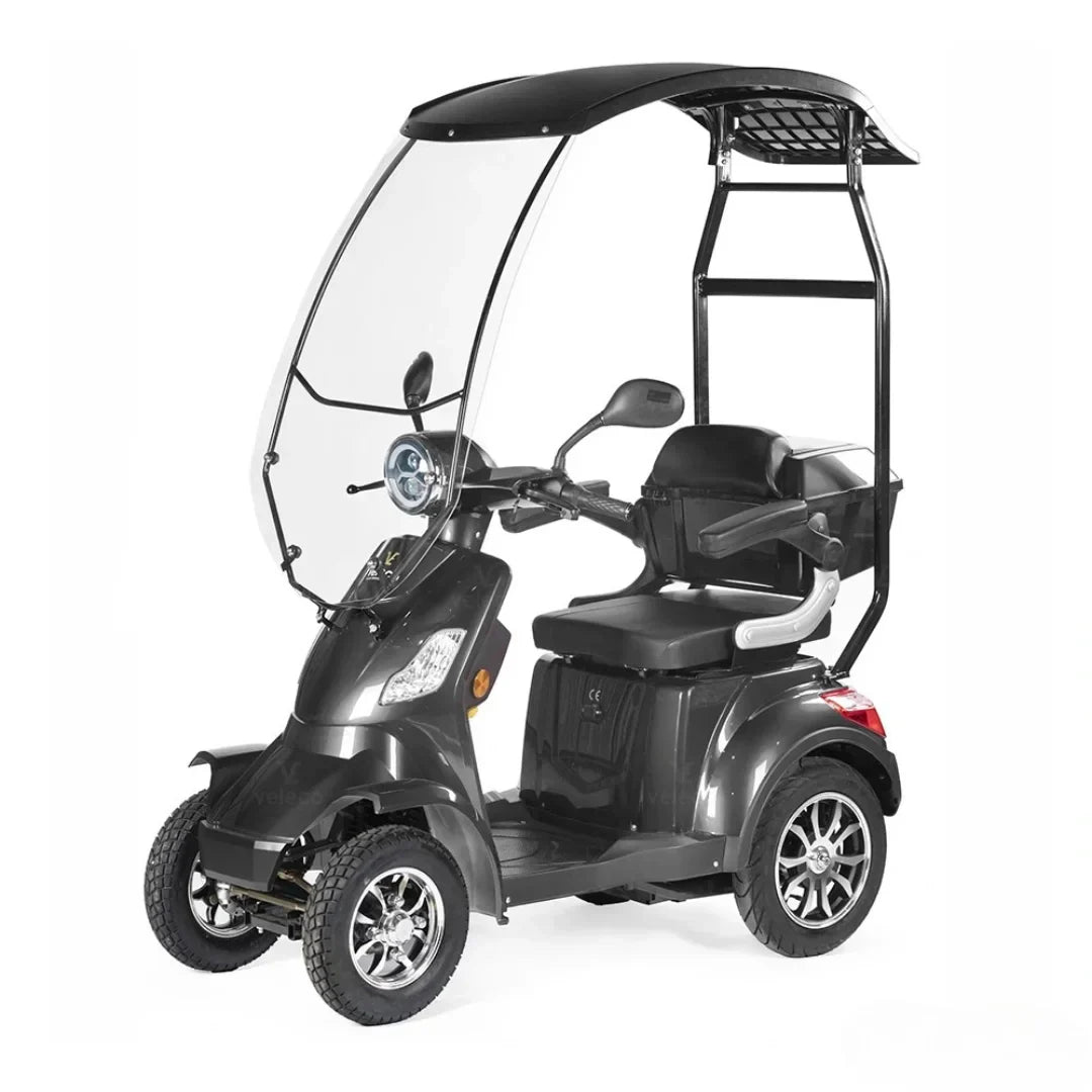 Izdelek na sliki je električni skuter, model Veleco Faster. Na sliki je prikazan triosni električni skuter s kabino, ki nudi zaščito pred vremenskimi vplivi. Ima udobno sedežno površino in je zasnovan za enostavno vožnjo, kar ga naredi primernega za različne uporabnike.