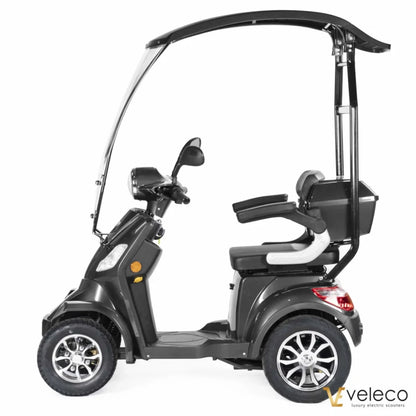 Izdelek na sliki je električni skuter, model Veleco Faster. Na sliki je prikazan stranski pogled skuterja, ki ima prostorno sedežno površino, zaščitni strešni del in udobno naslonjalo. Opremljen je s širokimi kolesi in ima moderno obliko, kar omogoča udobno vožnjo. Znamka Veleco je znana po luksuznih električnih skuterjih.