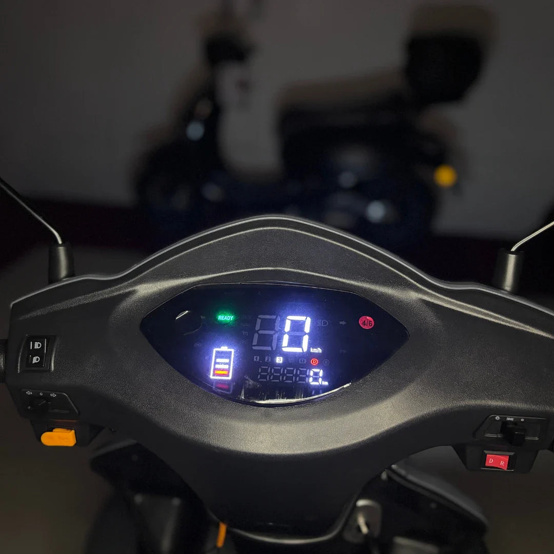 Izdelek je električni mobilni skuter, model Vigorous Vista Q1. Na sliki je prikazan nadzorni panel skuterja, ki vključuje digitalni zaslon s hitrostjo, nivojem baterije in drugimi informacijami. Vidna sta tudi stikala za upravljanje in indikatorji za delovanje. V ozadju je del skuterja, ki ni v fokusu.