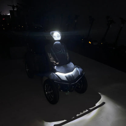 Izdelek na sliki je električni mobilni skuter z imenom Vigorous Vista Q1. Na sliki je vidna sprednja stran skuterja, ki ima svetlo na vrhu in elegantno obliko. Osvetlitev poudarja detajle na skuterju, medtem ko je ozadje temno, kar daje občutek modernosti in funkcionalnosti. Skuter je zasnovan za udobno in enostavno premikanje.