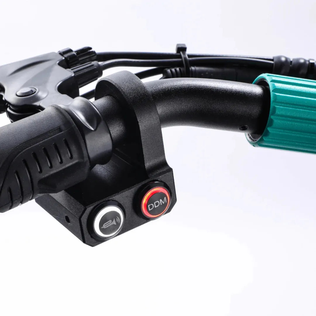 Izdelek na sliki je električni skiro, model Vsett 9. Na sliki so vidni ročaji skiroja z nadzorno ploščo, ki vključuje gumbe za upravljanje, kar omogoča enostavno prilagajanje hitrosti in funkcij med vožnjo. Ročaji so ergonomsko oblikovani za udobno držanje.