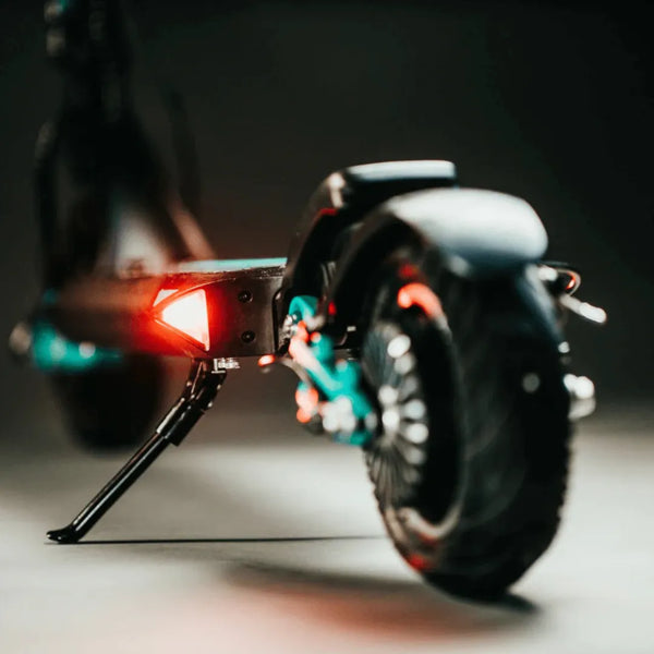 Izdelek na sliki je električni skiro, model Vsett 9. Na sliki je vidna zadnja stran skiroja, kjer so prikazani zadnji luči in nosilec za stojalo. Skira odlikujejo robustne pnevmatike in sodoben dizajn, kar nakazuje na njegovo uporabnost in zmogljivost.