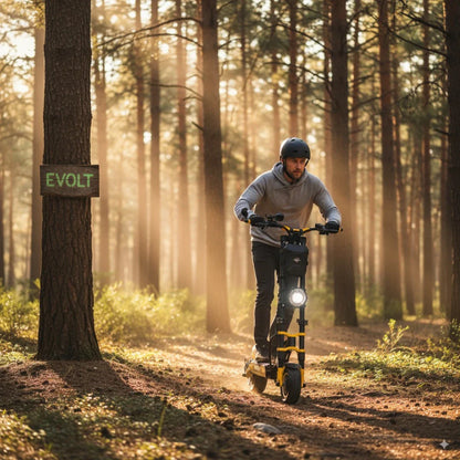 Na sliki je električni skiro model Vsett 11 Super. Vidimo moškega, ki vozi skiro po gozdni poti, obdanim z drevesi in naravno svetlobo. Moški nosi čelado in udobno obleko, skiro pa ima svetlo rumeno barvo ter sprednjo luč, kar nakazuje na njegovo uporabnost tudi v slabših svetlobnih pogojih. V ozadju je znak z napisom "EVOLT".