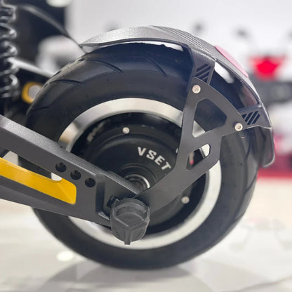 Na sliki je prikazan električni skiro znamke VSET, model 11 Super. Vidna je zadnja pnevmatika, ki je široka in ima profil za boljšo oprijemljivost. Prav tako je razvidna struktura okvirja in del motorja, kar kaže na robustno zasnovo skiroja. Dodatno je opaziti tudi amortizacijski sistem, ki pripomore k udobnejši vožnji.