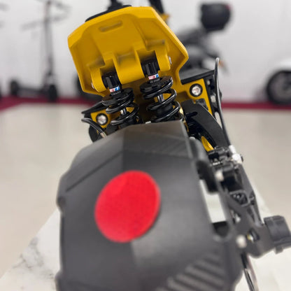 Izdelek na sliki je električni skiro znamke Vsett, model 11 Super. Na sliki je vidna podrobnost vzmetenja, ki vključuje dva črna vzmetna amortizerja, ter del zadnjega dela skiroja s rdečo odsevnico. Ozadje je nevtralno, kar omogoča osredotočenost na detajle skiroja.