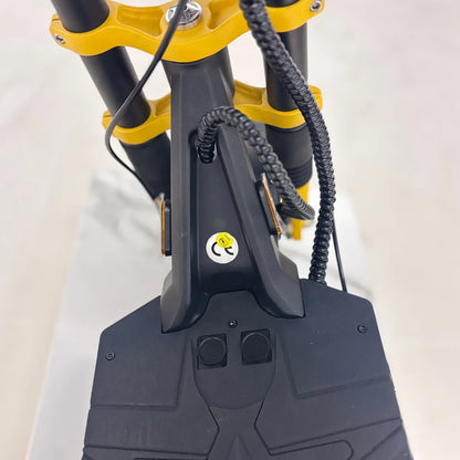 Izdelek na sliki je električni skiro, model Vsett 11 Super. Na sliki je vidna sprednja stran skiroja, kjer so prikazane ročice, nad katerimi je rumena aluminijasta konstrukcija. Na črni platformi so vidni gumbi za upravljanje ter oznaka CE, kar nakazuje skladnost z evropskimi standardi. Kabeli so urejeni in skrbno pritrjeni, kar prispeva k estetskemu videzu in varnosti.