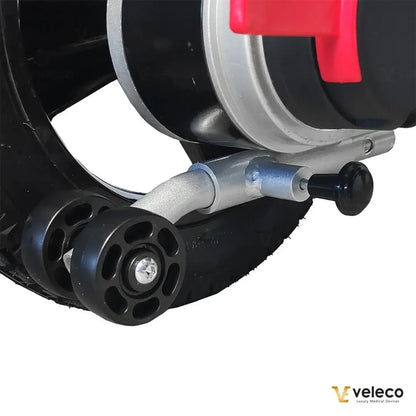 Izdelek je električni invalidski voziček znamke Veleco, model Cosmo. Na sliki je prikazan del vozička, ki vključuje kolo in del mehanizma, ki omogoča premikanje. Vidna sta tudi aluminijasta povezovalna cev in manjša kolesca, ki zagotavljajo stabilnost in enostavno manevriranje.