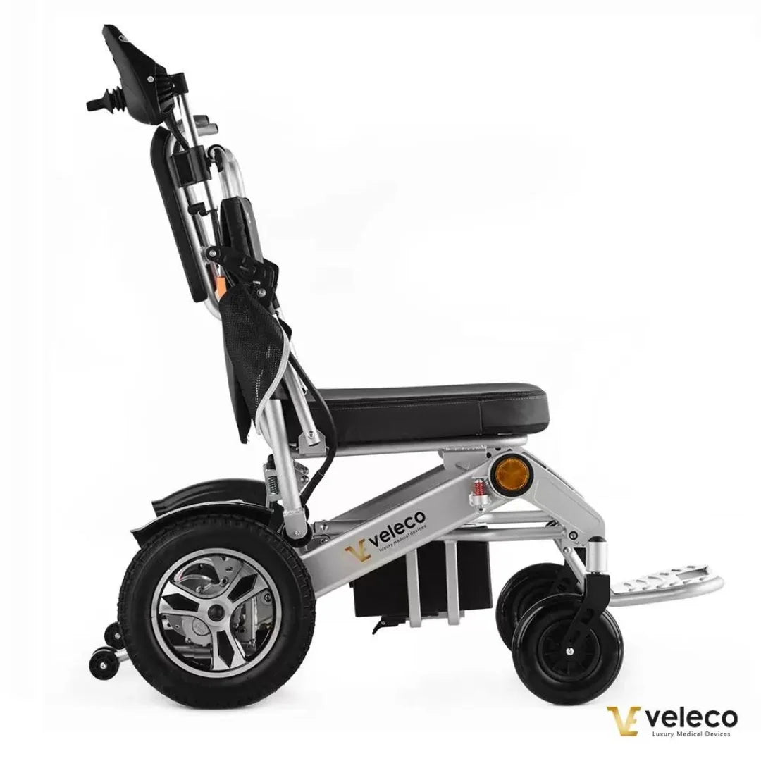 Izdelek je električni invalidski voziček znamke Veleco, model Cosmo. Na sliki je prikazan stranski pogled vozička, ki ima aluminijasto konstrukcijo, udobno sedežno površino in velike kolesa, kar omogoča enostavno premikanje. Vidna je tudi ročica za upravljanje in dodatni elementi, ki prispevajo k udobju uporabnika.