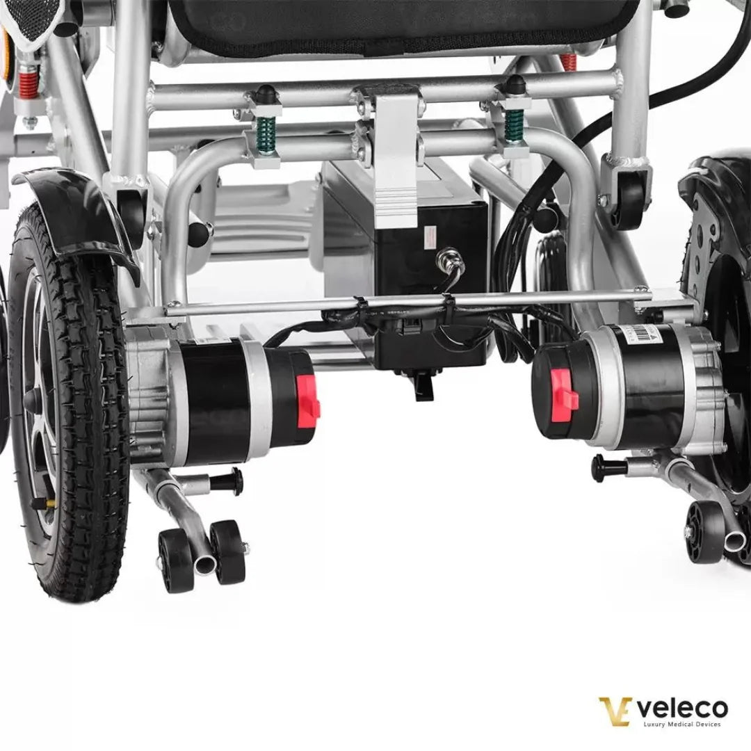 Posnetek od blizu električnega invalidskega vozička Veleco Cosmo, ki prikazuje njegova dvojna motorja in robusten okvir.