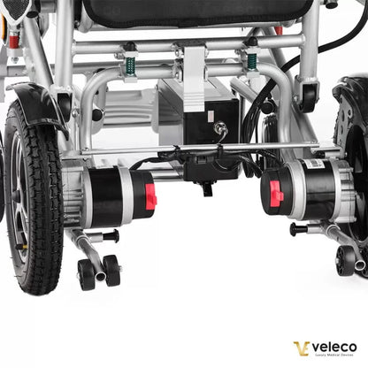 Posnetek od blizu električnega invalidskega vozička Veleco Cosmo, ki prikazuje njegova dvojna motorja in robusten okvir.