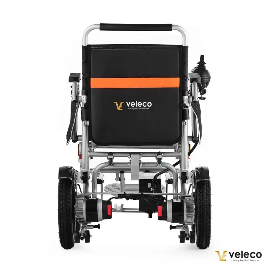 Izdelek je električni invalidski voziček, model Veleco Cosmo. Na sliki je prikazan zadnji del vozička, ki ima črno blazino z oranžnim pasom in logotipom znamke Veleco. Vidni so tudi zadnji kolesi in motorja, kar nakazuje na električni pogon. Voziček je zasnovan za udobno in enostavno uporabo.