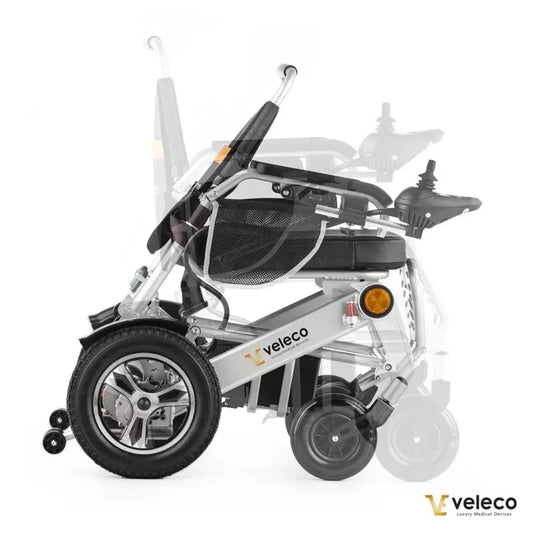 Izdelek na sliki je električni invalidski voziček znamke Veleco, model Cosmo. Na sliki je prikazan voziček v kompaktnem, zloženem stanju, kar omogoča enostavno prenašanje in shranjevanje. Vidne so tudi njegove kolesne strukture ter upravljalne ročice, kar nakazuje na uporabnost in udobje pri vožnji.