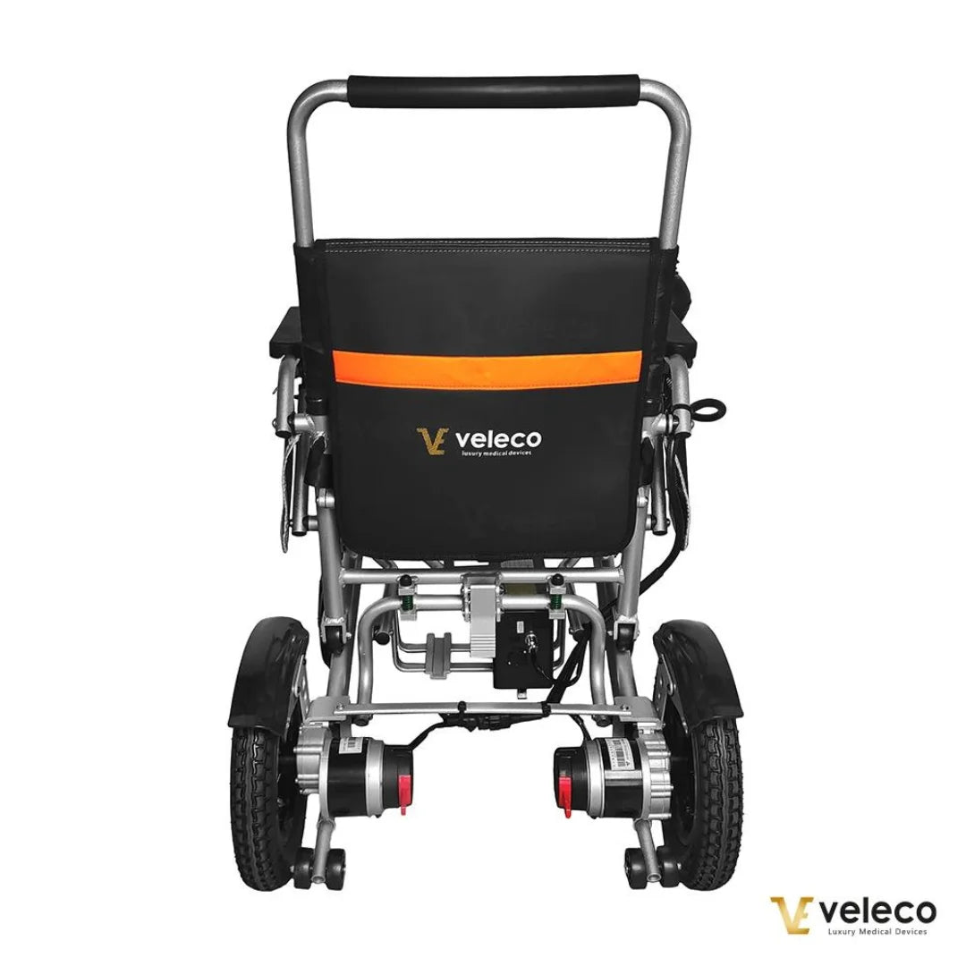 Izdelek je električni invalidski voziček, model Veleco Cosmo. Na sliki je prikazan zadnji del vozička, ki ima robustno aluminijasto konstrukcijo in udobno naslonjalo. Opremljen je z dvema motorjema na zadnjih kolesih ter ima tudi ročaj za enostavno upravljanje. Znamka Veleco je vidna na hrbtni strani vozička, kar nakazuje na kakovost in zanesljivost izdelka.