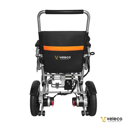 Izdelek je električni invalidski voziček, model Veleco Cosmo. Na sliki je prikazan zadnji del vozička, ki ima robustno aluminijasto konstrukcijo in udobno naslonjalo. Opremljen je z dvema motorjema na zadnjih kolesih ter ima tudi ročaj za enostavno upravljanje. Znamka Veleco je vidna na hrbtni strani vozička, kar nakazuje na kakovost in zanesljivost izdelka.