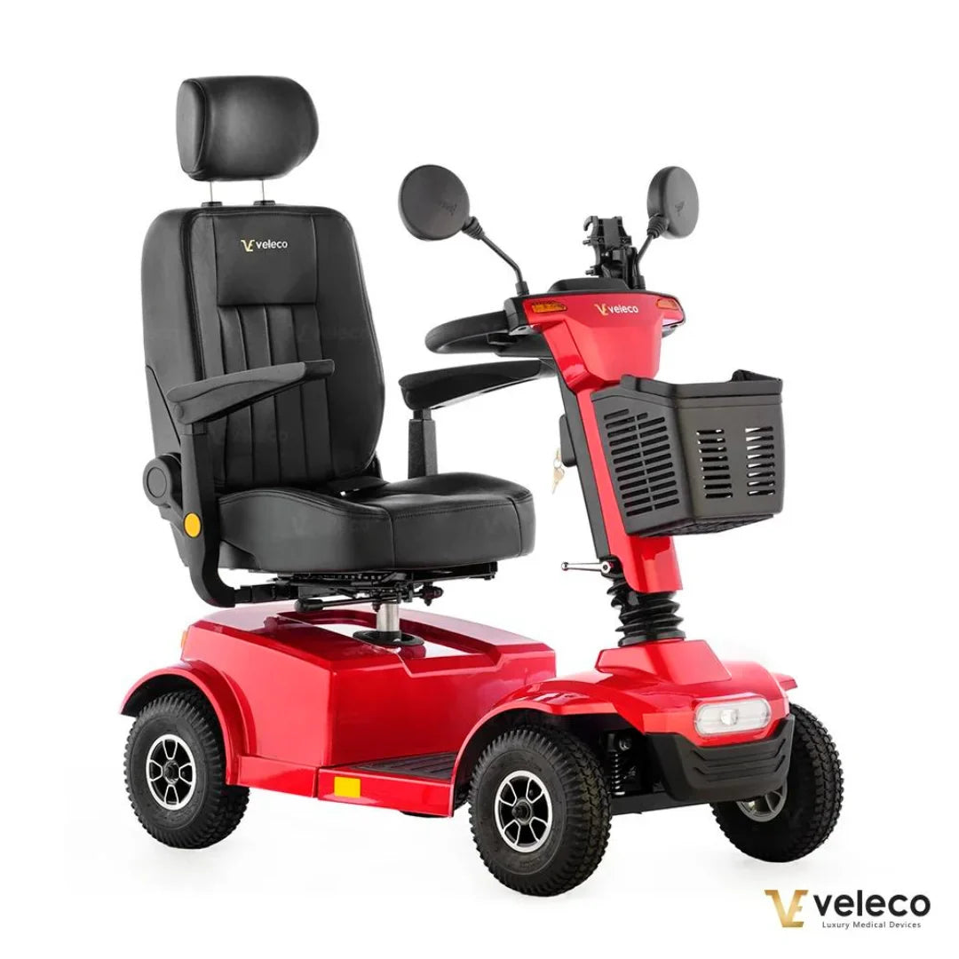 Izdelek na sliki je električni skuter, model Veleco Jumpy. Skuter je v rdeči barvi in ima udobno sedežno površino s naslonjalom ter naslonoma za roke. Na sprednjem delu je nameščen košarica za shranjevanje, vidne so tudi ogledala za boljšo vidljivost. Ta električni skuter je zasnovan za udobno in varno vožnjo.