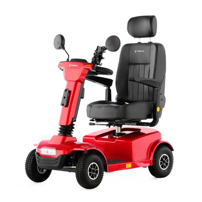 Izdelek na sliki je električni skuter, model Veleco Jumpy. Ima udobno sedežno površino s naslonjalom in naslonoma za roke, kar omogoča enostavno in udobno vožnjo. Skuter je v svetlo rdeči barvi in je zasnovan za enostavno manevriranje, kar je prikazano z njegovimi manjšimi kolesi in kompaktnim oblikovanjem.