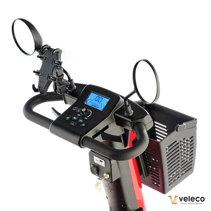 Izdelek je električni skuter, model Veleco Jumpy. Na sliki je prikazan krmni del skuterja, ki vključuje digitalni zaslon, ročaje s ogledali ter košarico za shranjevanje. Zaslon prikazuje hitrost, kar je uporabno za nadzor med vožnjo. Skuter je zasnovan za udobno in varno vožnjo.