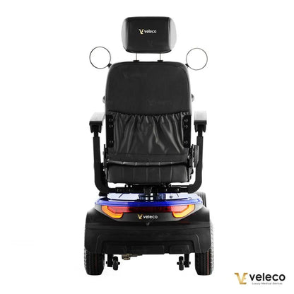 Izdelek je električni skuter, specifično model "Looper" znamke Veleco. Na sliki je prikazana zadnja stran skuterja, ki ima udobno sedežno površino in naslonjalo, ter ogledala na obeh straneh. Vidni so tudi zadnji luči in kolesa, kar nakazuje na funkcionalnost in stabilnost vozila. Skuter je zasnovan za udobno in varno mobilnost.