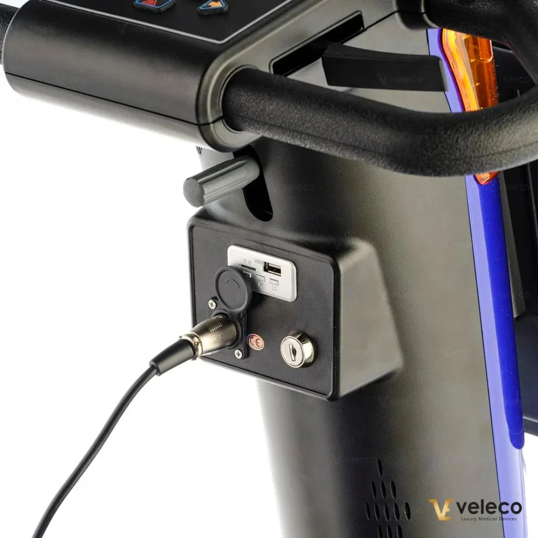 Izdelek na sliki je električni skuter, model Veleco Looper. Vidna je kontrolna plošča s priključki, vključno z USB vhodom in ključavnico. Skuter ima tudi ročaj, kar omogoča udobno vožnjo. Na sliki so dodatne funkcionalnosti, ki pripomorejo k enostavni uporabi in polnjenju.