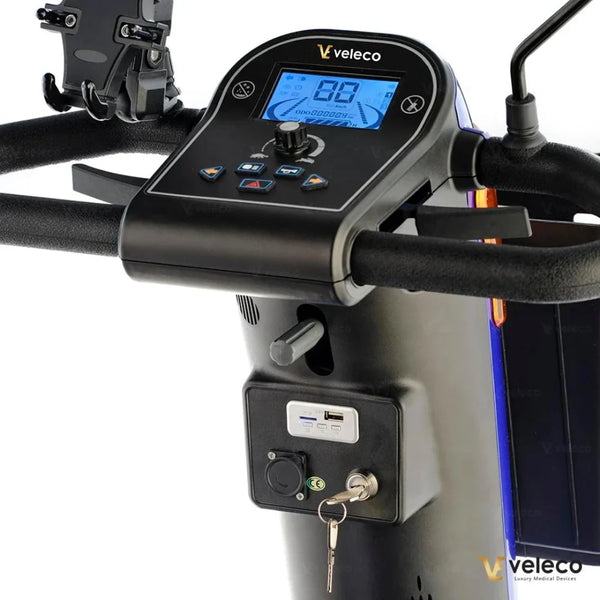 Izdelek na sliki je električni skiro, model Veleco Looper. Na sliki je prikazano krmilo skiroja z digitalnim zaslonom, ki prikazuje hitrost in druge informacije. Vidni so tudi gumbi za upravljanje, ključavnica ter USB priključek, kar nakazuje na dodatne funkcionalnosti in udobje pri uporabi.