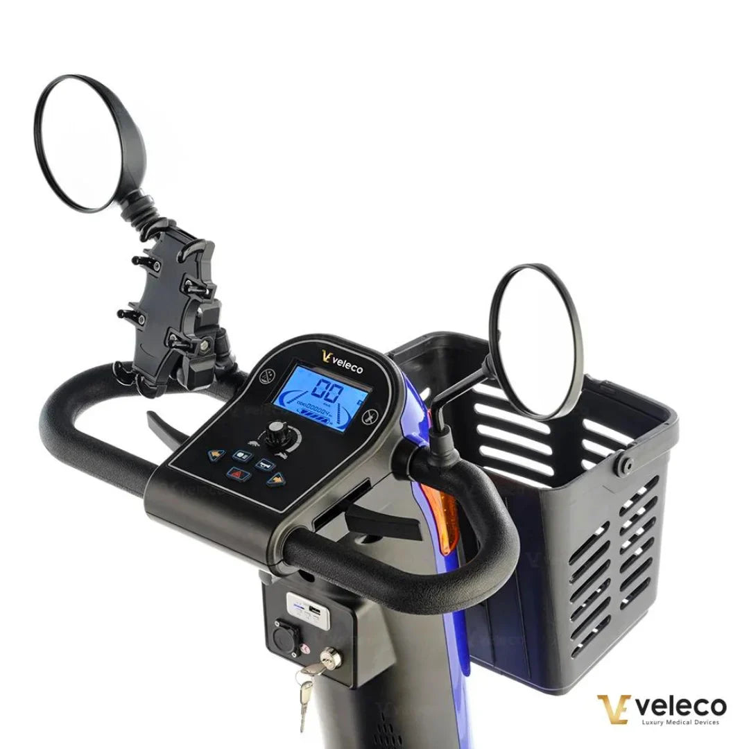 Izdelek je električni skuter, znamke Veleco, model Looper. Na sliki je prikazan krmni del skuterja, kjer so vidni digitalni zaslon, ročaji in ogledali. Ob strani je tudi košara za shranjevanje, kar omogoča dodatno funkcionalnost pri vožnji.