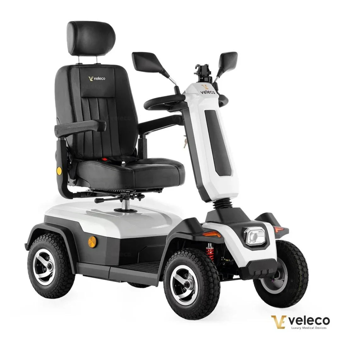 Izdelek na sliki je električni skuter, natančneje model Veleco Sharpy. Na sliki je prikazan skuter z udobnim sedežem in naslonjalom, ki je zasnovan za udobno vožnjo. Ima tudi krmilo z ročicami in sprednje luči, kar nakazuje na njegovo uporabnost v različnih okoljih. Kolesa so robustna, kar omogoča stabilnost in enostavno premikanje.
