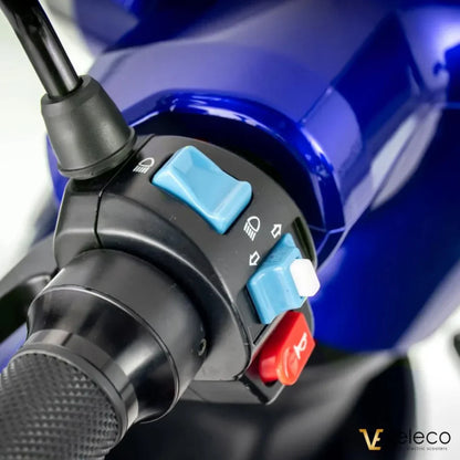 Izdelek na sliki je električni mobilni voziček, model Veleco ZT15. Na sliki so vidni upravljalni gumbi, ki vključujejo stikala za luči in druge funkcije, kar nakazuje na enostavno uporabo. Barvna kombinacija in dizajn vozička so moderni, kar prispeva k njegovi privlačnosti.