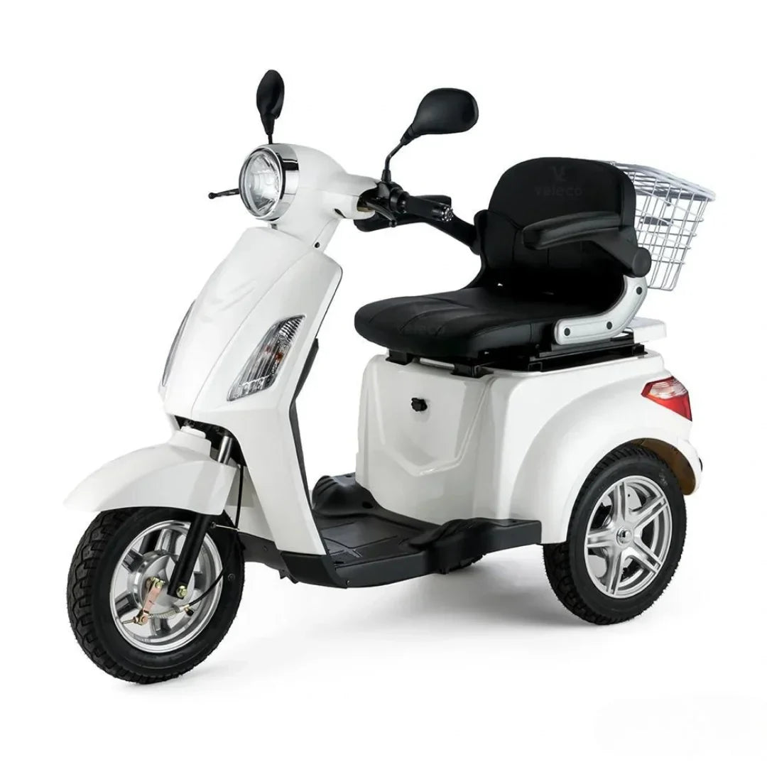 Izdelek je električni mobilni voziček, model Veleco ZT15. Na sliki je prikazan voziček bele barve s širokim sedežem in ročaji. Ima tri kolesa, kar zagotavlja stabilnost, ter sprednje luči in ogledala. Na zadnjem delu se nahaja košara za shranjevanje, kar omogoča praktičnost pri uporabi. Voziček je zasnovan za udobno vožnjo in enostavno upravljanje.
