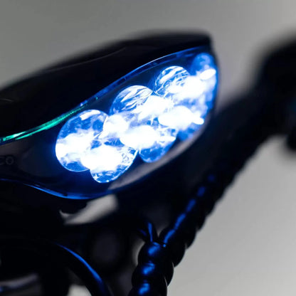 Izdelek je električni mobilni voziček, model Veleco ZT16. Na sliki je prikazan del vozička, osvetljen z močnimi LED lučmi, ki so nameščene na sprednjem delu. Luči so modre barve in so zasnovane za izboljšanje vidnosti med vožnjo. Celoten dizajn vozička je eleganten in sodoben.