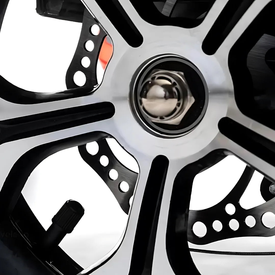 Izdelek je električni mobilni voziček, model Veleco ZT16. Na sliki je prikazan del kolesa, ki vključuje aluminijasto platišče z večkrakim dizajnom in vidno matično vijak. Kolo ima tudi odprtine, kar lahko pripomore k zmanjšanju teže in izboljšanju aerodinamike. Celoten izgled kaže na sodobno in robustno zasnovo, primerno za mobilnost.