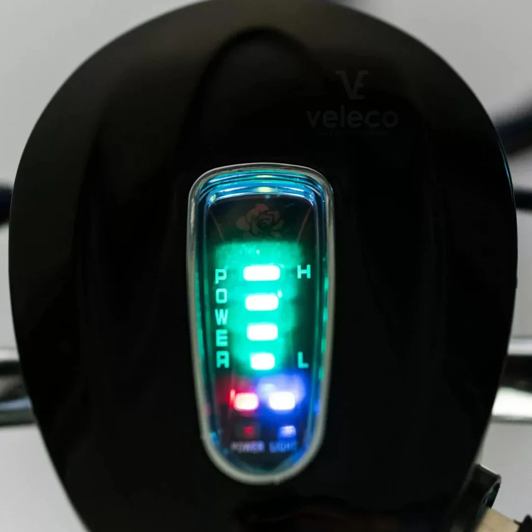 Izdelek je električni mobilni voziček, model Veleco ZT16. Na sliki je prikazan del nadzorne plošče, kjer so vidni LED indikatorji za moč in nivo baterije. Indikatorji so osvetljeni v različnih barvah, kar uporabniku omogoča enostavno spremljanje stanja vozička. Znamka Veleco je znana po svojih električnih mobilnih rešitvah.
