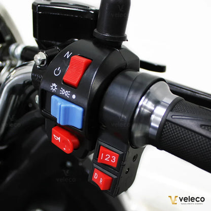 Izdelek na sliki je električni mobilni voziček, model Veleco ZT63. Na sliki so vidni upravljalni elementi, vključno z gumbi za smer vožnje, luči in nastavitvami hitrosti. Voziček je zasnovan za enostavno upravljanje in udobno vožnjo.