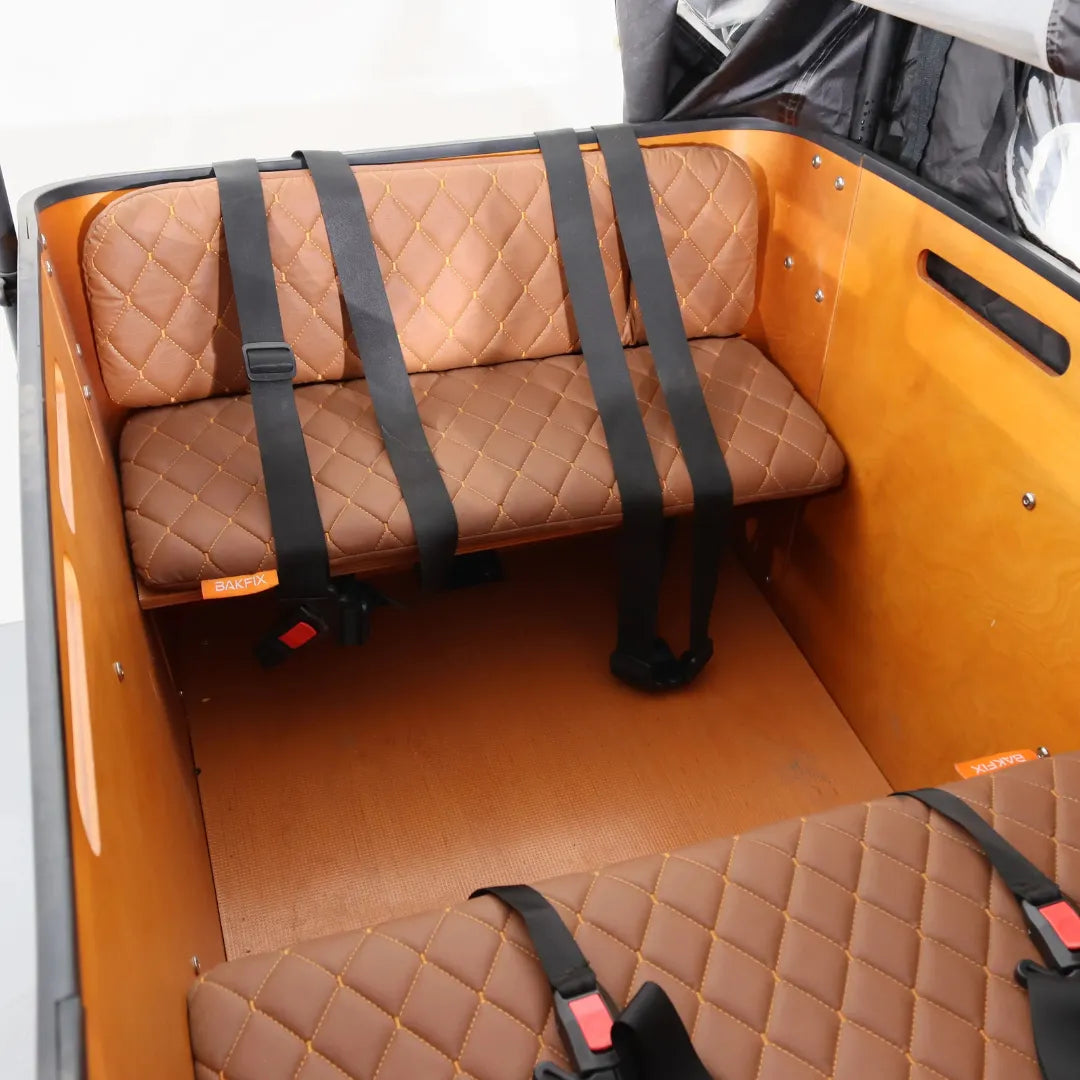 Notranji pogled električnega kolesa Vogue Cargo 3, ki prikazuje rjavo prešito sedišče in varnostne pasove.