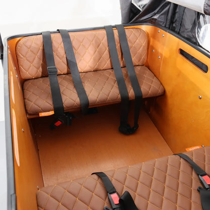 Notranji pogled električnega kolesa Vogue Cargo 3, ki prikazuje rjavo prešito sedišče in varnostne pasove.