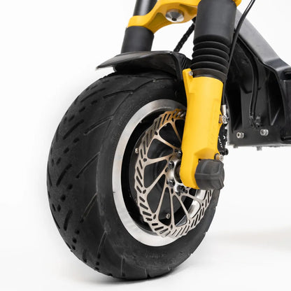 Na sliki je električni skiro znamke Vsett, model 11 Super. Vidna je sprednja pnevmatika z robustnim profilom, ki je primerna za različne terene. Poleg tega je na sliki prikazan tudi sistem zaviranja z disk zavornim mehanizmom, kar zagotavlja učinkovito ustavljanje. Rumeni detajli na sprednjem delu skiroja dodajajo dinamičen videz.