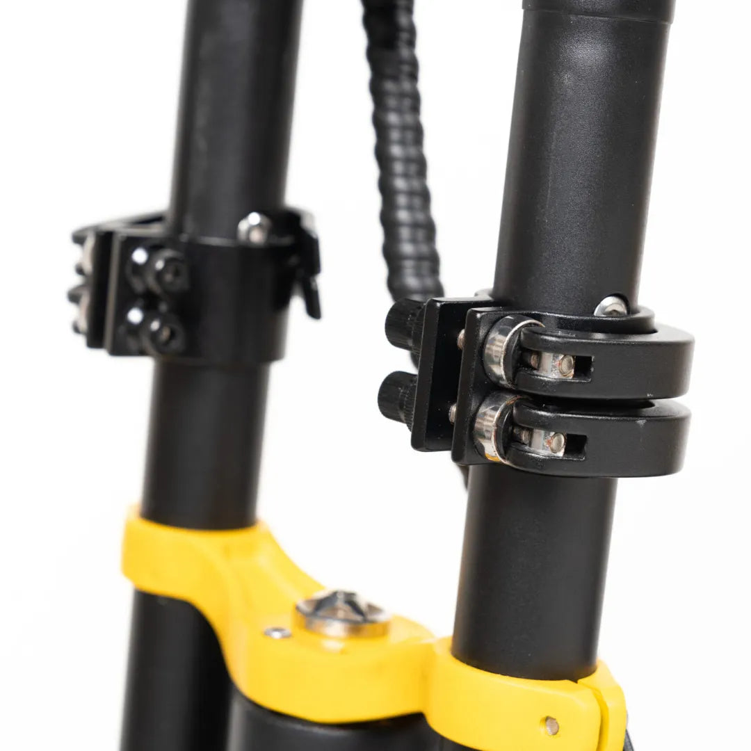 Izdelek je električni skiro, model Vsett 11 Super. Na sliki so vidni deli okvirja skiroja, vključno z zaponkami in povezovalnimi elementi, ki zagotavljajo stabilnost in varnost. Barvna kombinacija črne in rumene dodaja dinamičen videz.