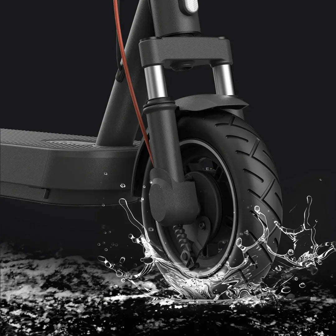 Izdelek na sliki je električni skiro, znamke Xiaomi, model 5 Pro. Na sliki je prikazana sprednja kolesa skiroja, ki se pelje po vodi, kar poudarja njegovo vodoodpornost in zmogljivost na različnih površinah. Vidna je tudi robustna konstrukcija in detajli na kolesu, kar kaže na kakovost izdelave.