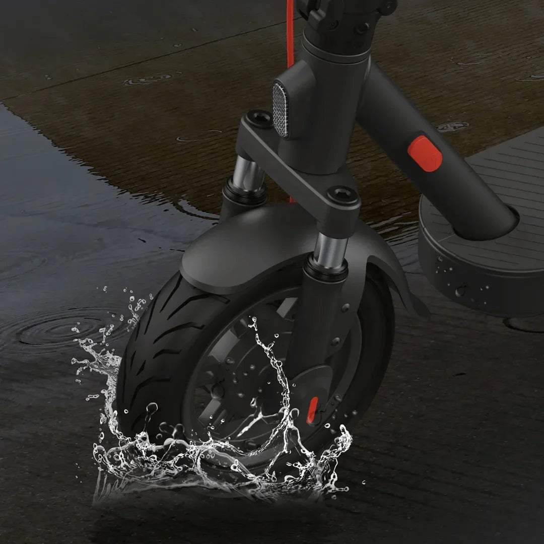 Izdelek je električni skiro znamke Xiaomi, model Elite. Na sliki je vidna sprednja kolesa skiroja, ki se pelje po mokri površini, pri čemer se voda brizga okoli kolesa. Kolo ima gumirano pnevmatiko z izrazitim profilom, kar omogoča boljši oprijem na različnih površinah. Vidni so tudi delčki okvirja in vzmetenja skiroja.