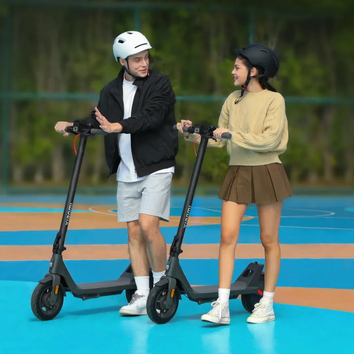 Dva mlada odrasla na električnem skiroju Xiaomi 4 Lite 2nd Gen, nasmejana na pisani podlagi.