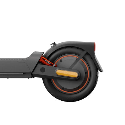 Na sliki je električni skiro znamke Xiaomi, model 5 Max GL. Vidna je zadnja kolesa skiroja, ki ima robustno pnevmatiko in reflektor za večjo varnost. Ohišje je v temno sivi barvi, na kolesu pa je tudi rdeč detajl, kar daje skiroju sodoben videz.