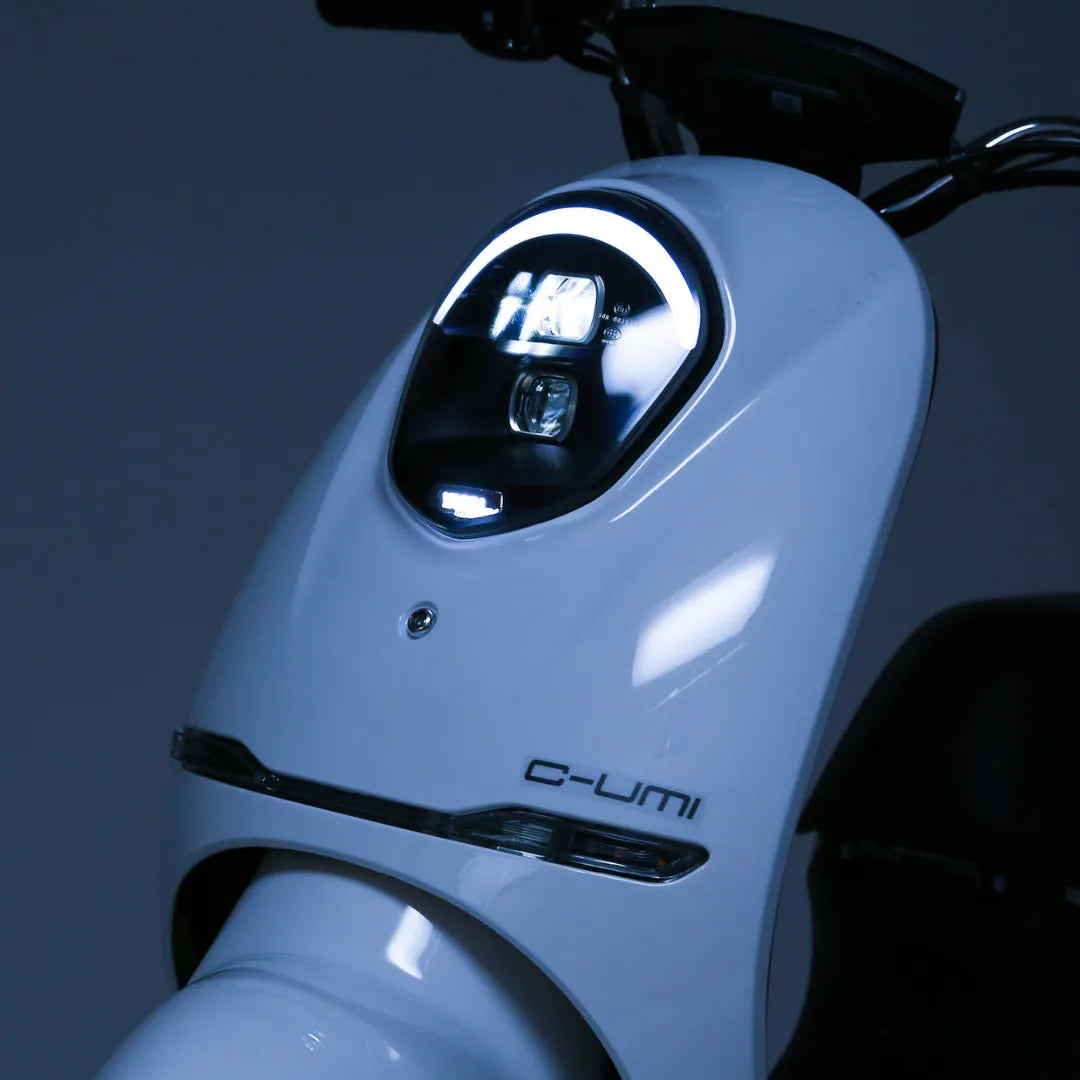 Od blizu električni skuter Yadea C Umi, ki prikazuje njegovo elegantno obliko in osvetljen žaromet