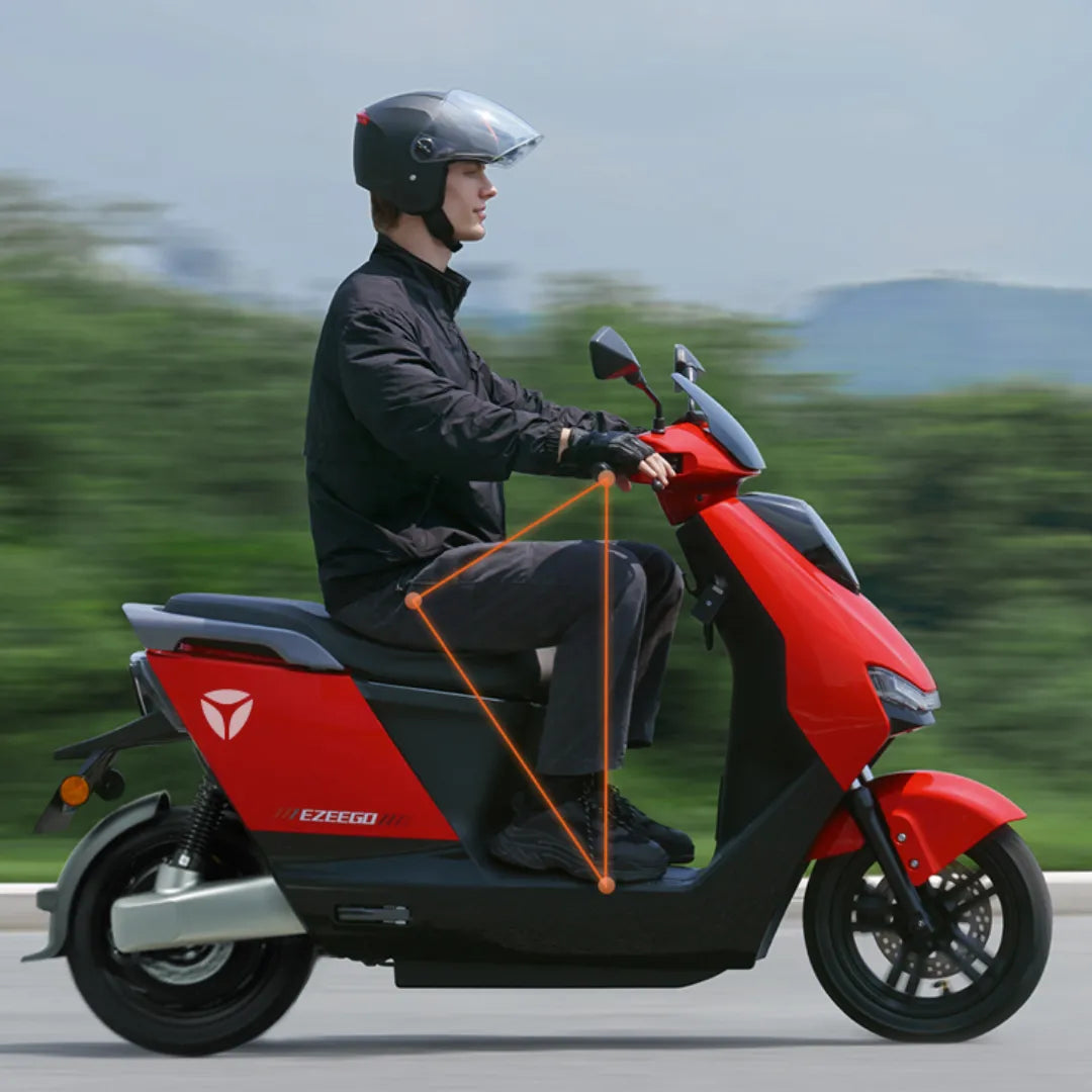 Oseba se vozi z električnim skuterjem Yadea Ezeego po slikoviti cesti.