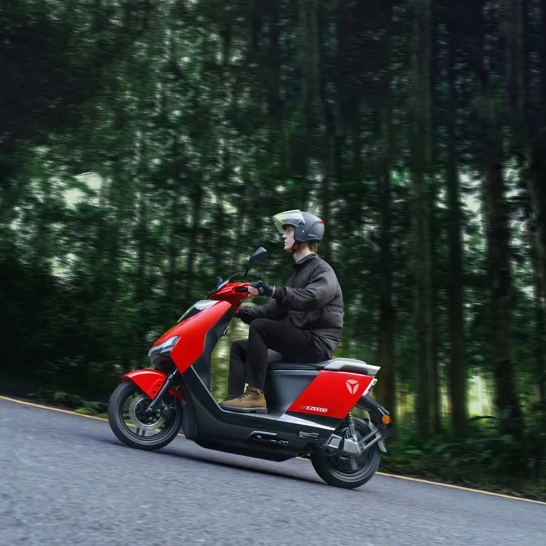 Voznik električnega skuterja Yadea Ezeego se vozi po gozdni cesti.