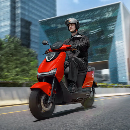 Voznik električnega skuterja Yadea Ezeego se hitro premika skozi moderno mestno pokrajino.