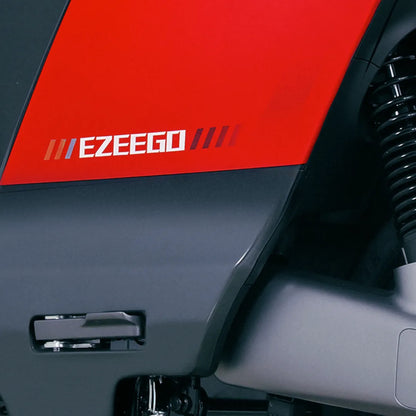 Od blizu logotip električnega skuterja Yadea Ezeego na elegantnem rdeče-sivem ohišju.