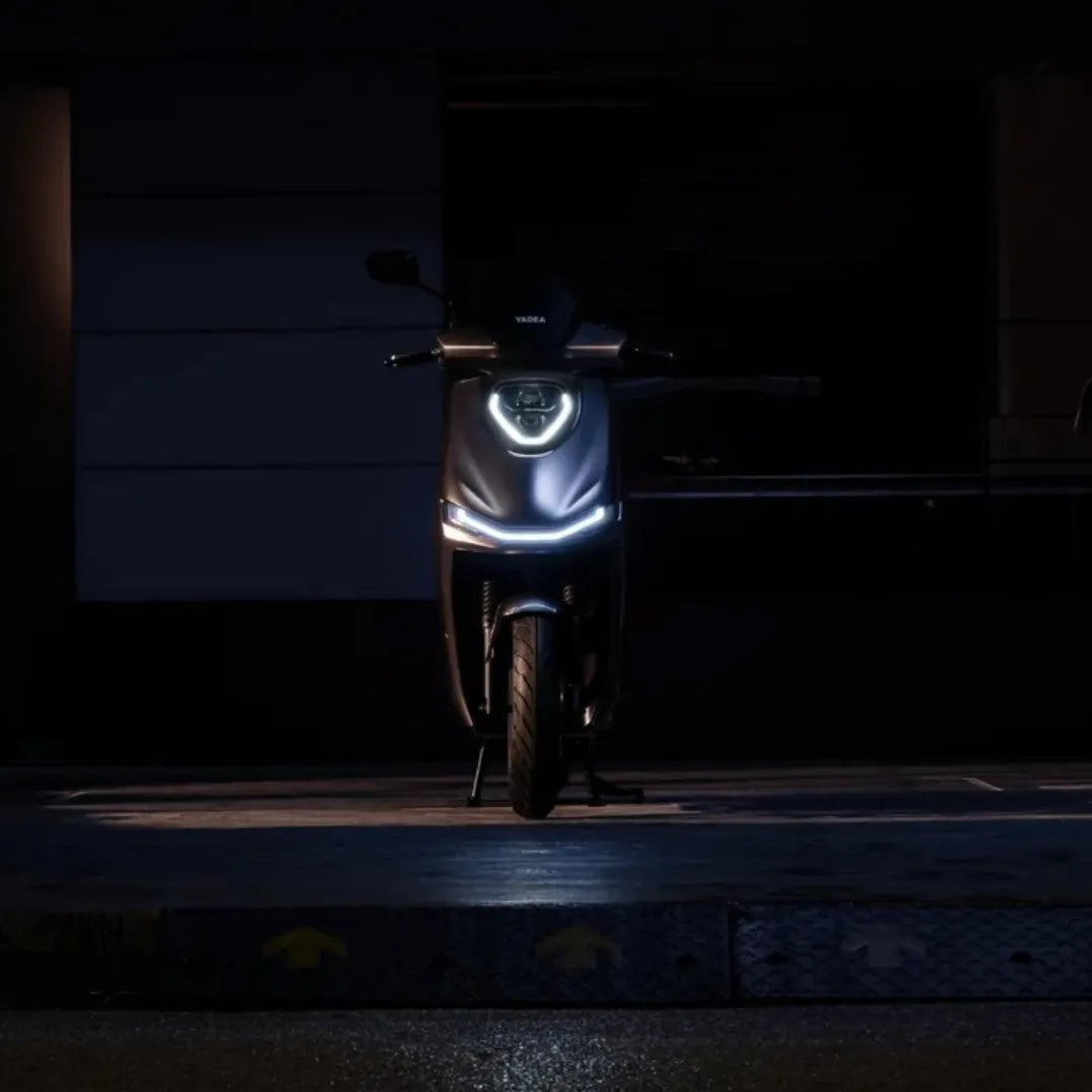 Električni skuter Yadea Fierider osvetljen v temi, ki poudarja njegovo elegantno obliko.