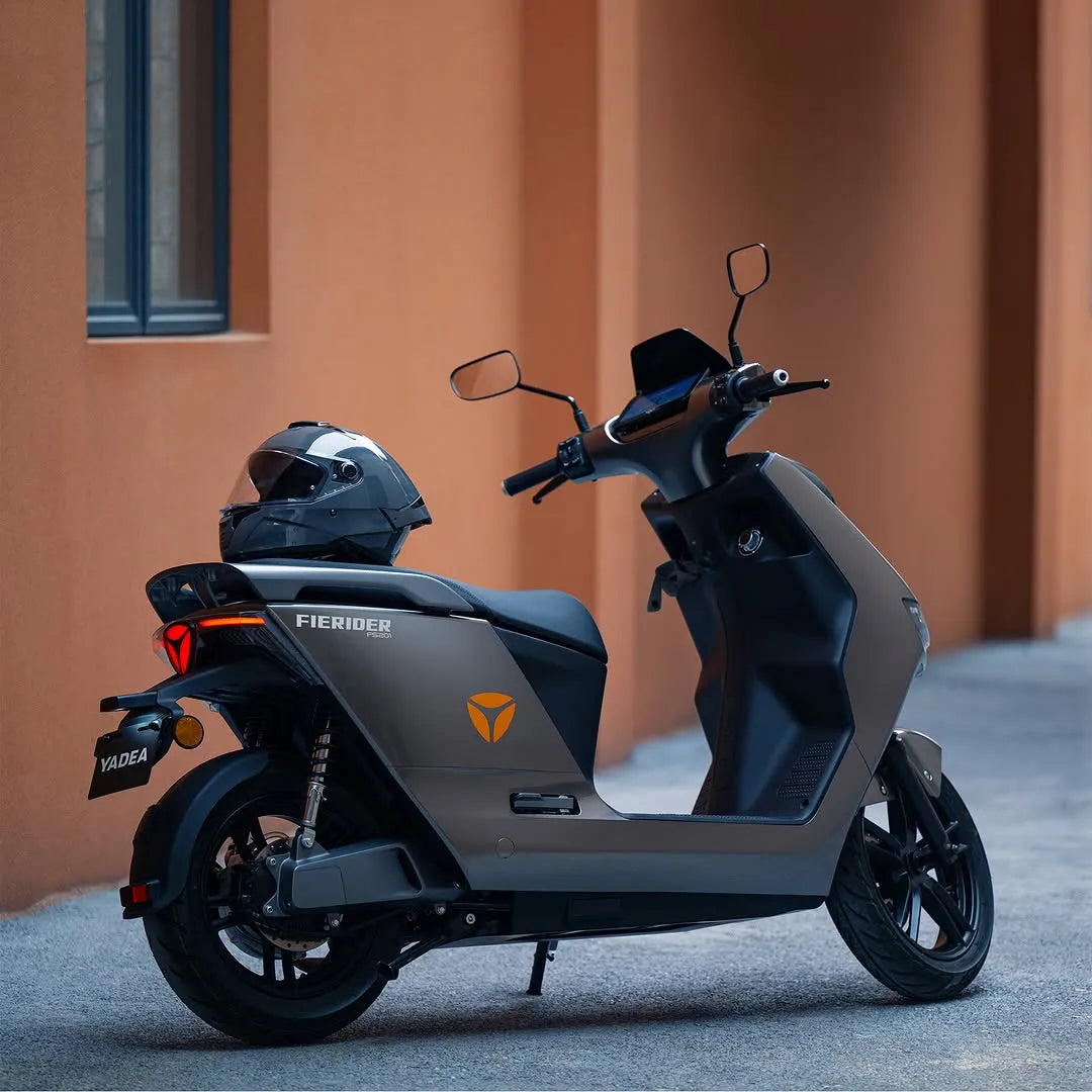 Električni skuter Yadea Fierider parkiran ob steni, ki prikazuje njegovo elegantno obliko.