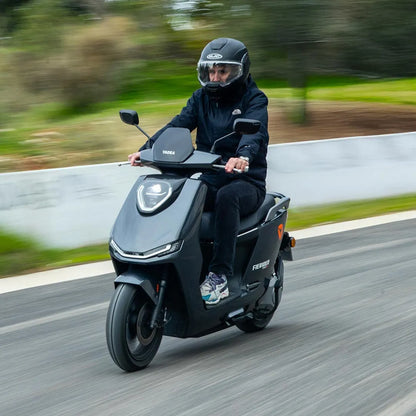 Voznik s čelado vozi električni skuter Yadea Fierider po vijugasti cesti.