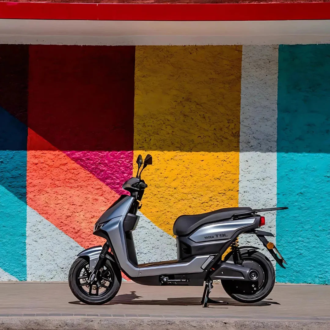 Električni skuter Yadea T9L parkiran ob živahni, pisani steni.